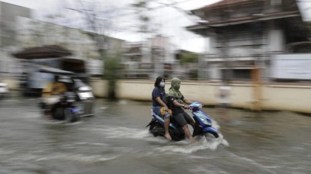 Un scooter traverse une rue inondée en Thaïlande après de fortes pluies