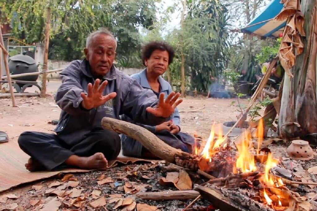 Des thaïlandais se réchauffent près d'un feu