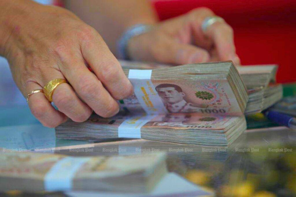 Un employé compte des liasses de billets de 1 000 bahts dans un magasin d'or à Yaowarat.