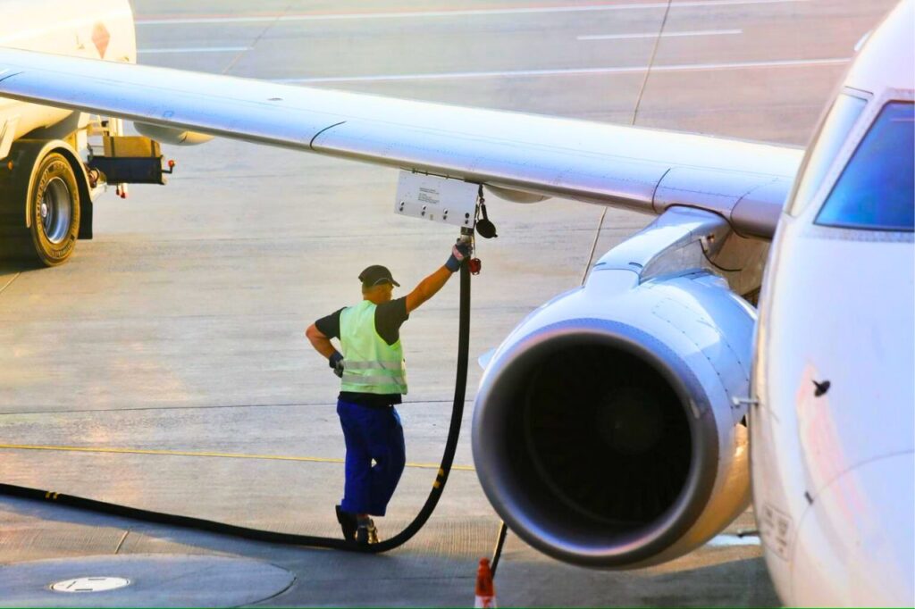 Employé ravitaillant en carburant un avion sur le tarmac d’un aéroport