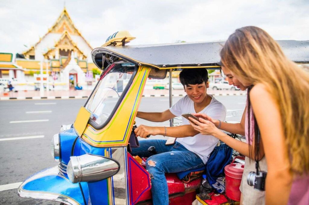 Des touristes indiquent leur destination à un chauffeur de tuk tuk.
