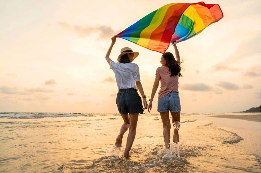 Femmes sur une plage avec le drapeau LGBTQIA+