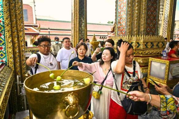 Des touristes chinois trempent des bulbes de lotus dans un bol d'eau au Grand Palais de Bangkok