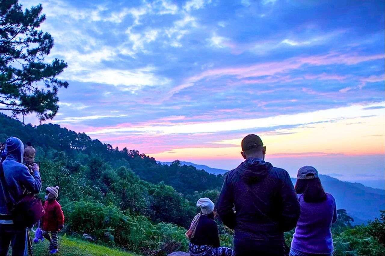 Des touristes observent le lever du soleil sur une montagne de Thaïlande