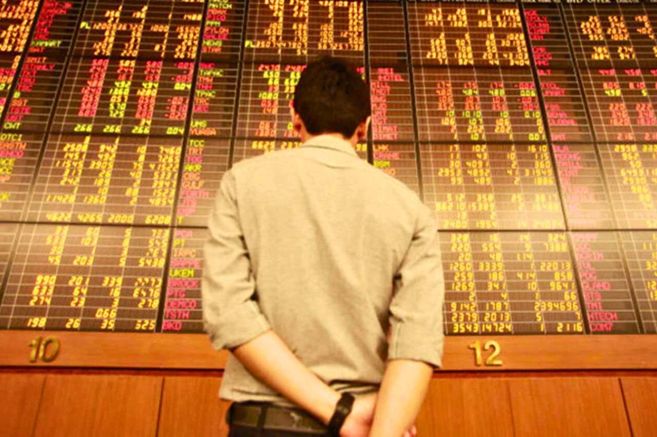 Ein Investor betrachtet eine Aktientafel in einem Handelsraum