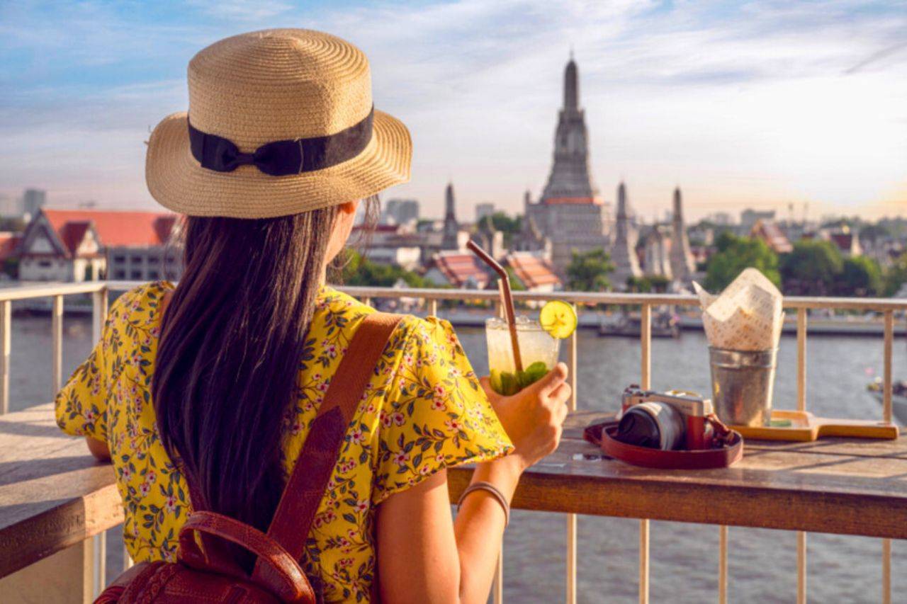 Une touriste boit un verre dans un bar en face du temple Wat Arun à Bangkok