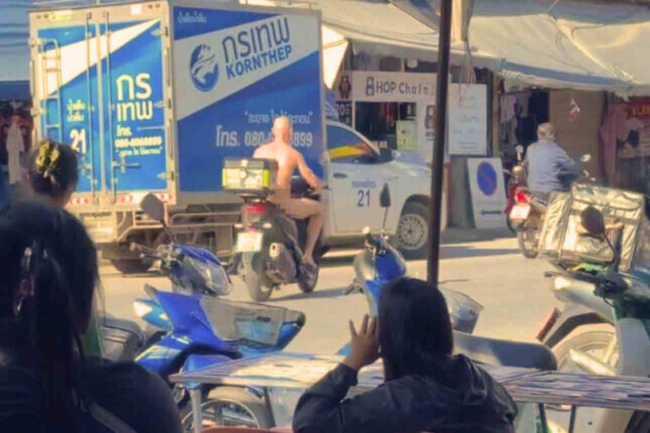 Un habitant filme un étranger entièrement nu repartant à moto après s’être arrêté dans une supérette du marché de Khlong Lan à Kamphaeng Phet, le 16 novembre 2025.