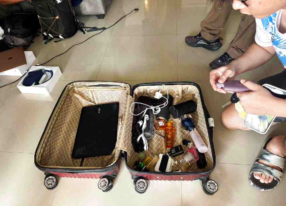 Un homme de Chiang Mai vérifie ses affaires récupérées à l'intérieur de la résidence du suspect français sur Koh Samui alors que la police effectue une perquisition le 27 novembre 2025