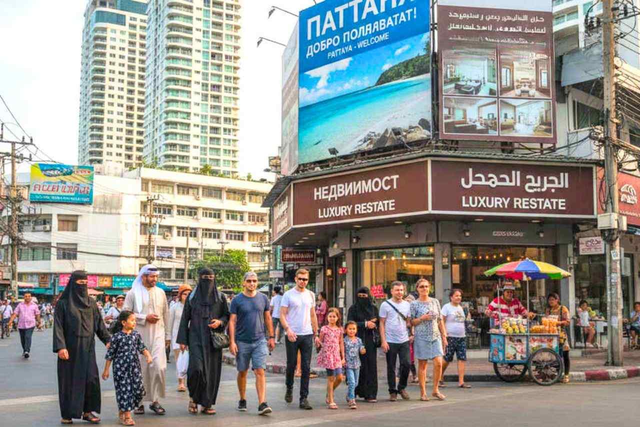 Shopfronts displaying foreign languages and passersby of several nationalities in a street in Pattaya
