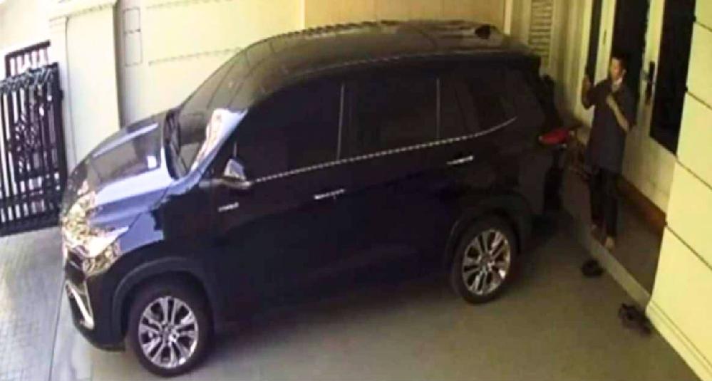 La femme de ménage filmée par une caméra de surveillance prenant des photos dans le garage