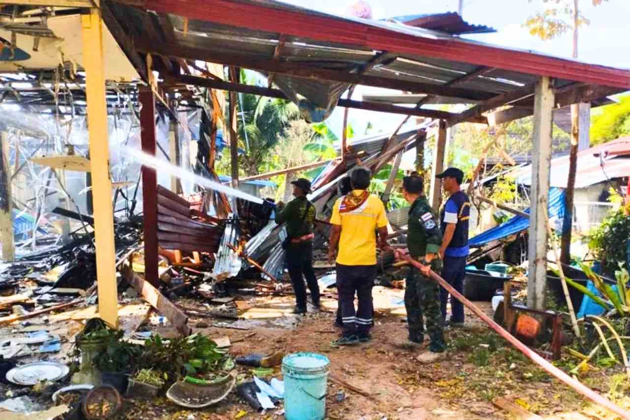 Local security forces control the fire of a house hit by a Cambodian rocket in Kantharalak district, Si Sa Ket province, on December 14, where a Thai was killed by shrapnel