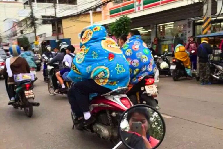Des habitants de Bangkok bien emmitouflés roulent à moto lors d’une vague de froid en Thaïlande
