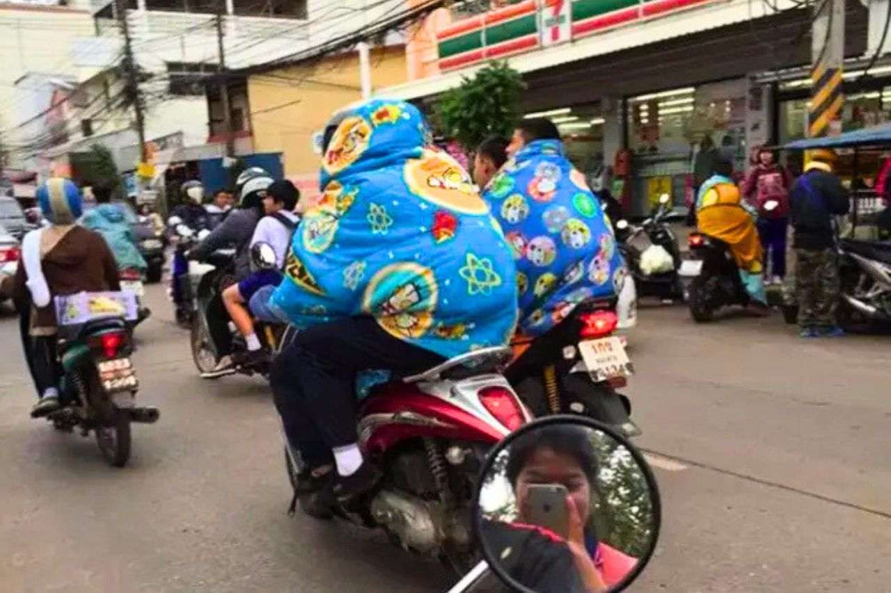 Des habitants de Bangkok bien emmitouflés roulent à moto lors d’une vague de froid en Thaïlande