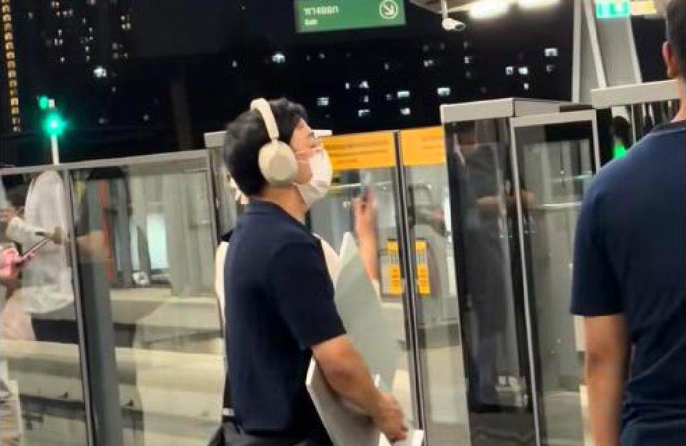 Homme avec un ordinateur Mac desktop dans une station du BTS à Bangkok