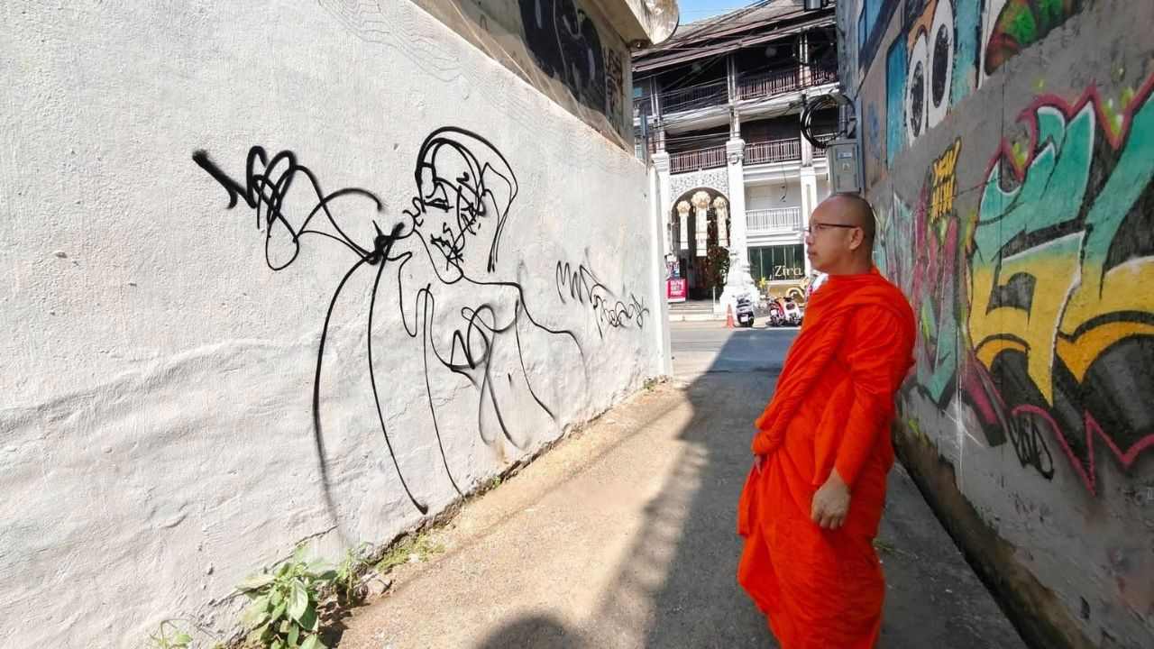 A monk in front of the graffiti on the wall of Wat Dok Euang temple in Chiang Mai