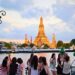 Touristes prenant des photos devant le temple Wat Arun à Bangkok au coucher du soleil