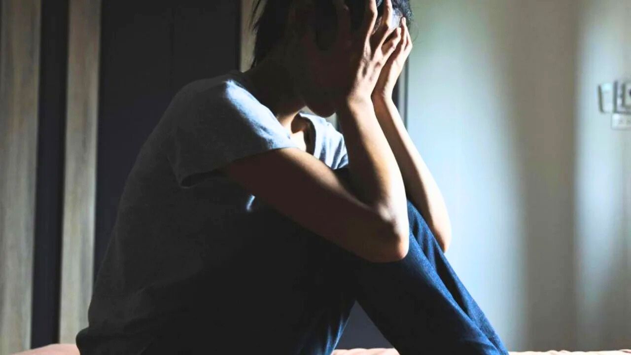 Jeune personne assise, tête dans les mains