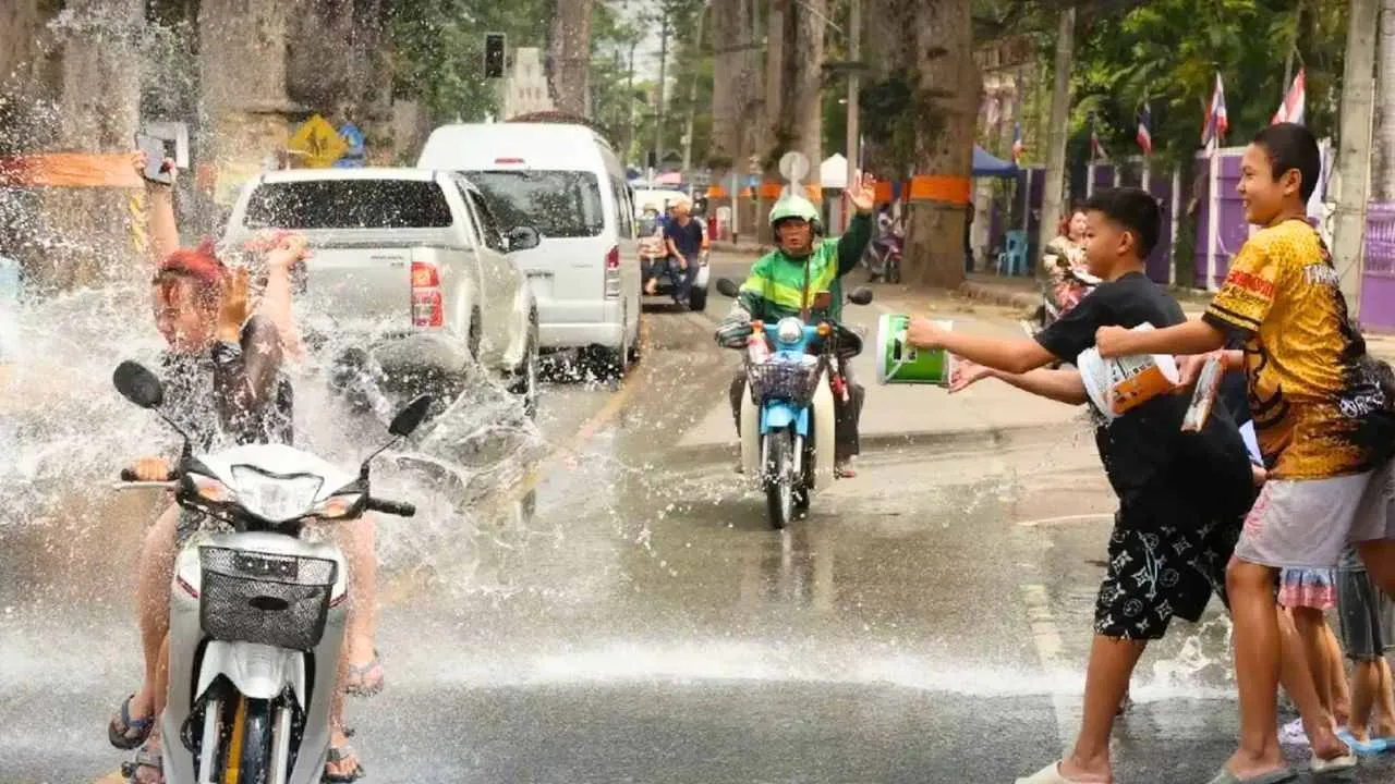 Jeunes lançant de l’eau sur des motards en pleine circulation pendant le Songkran en Thaïlande
