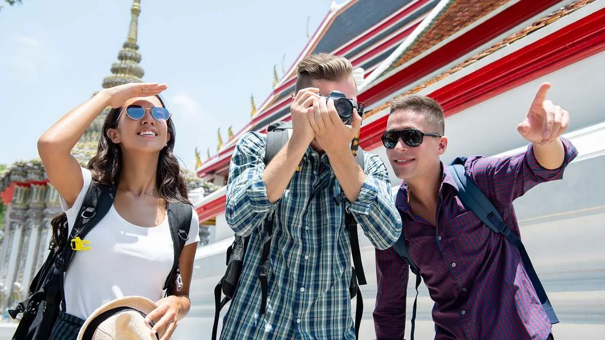 Touristes étrangers visitant un temple en Thaïlande et prenant des photos lors d’un séjour touristique