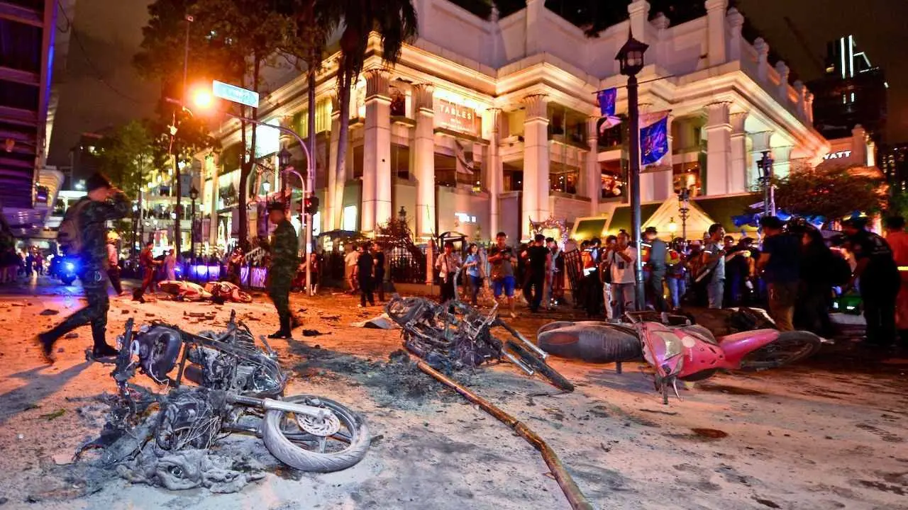 Des soldats thaïlandais inspectent les dégâts causés par l'attentat à la bombe du sanctuaire d'Erawan à Bangkok, avec des motos calcinées au premier plan