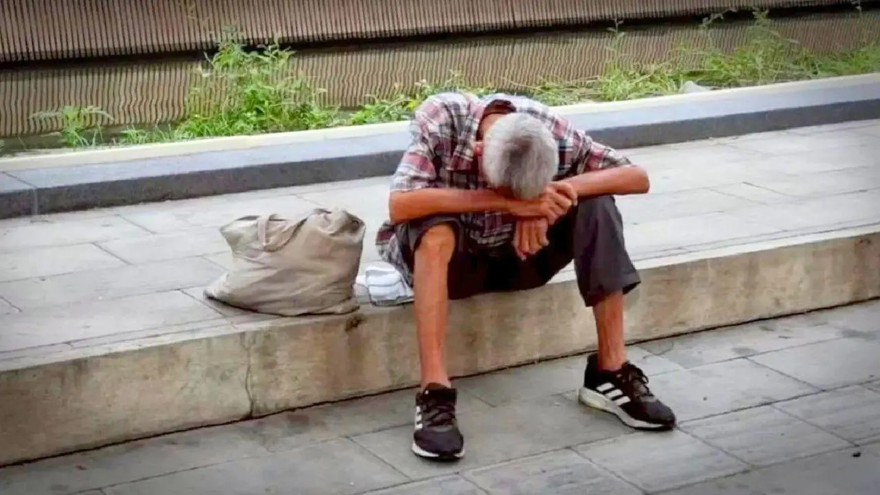 Étranger sans-abri assis sur un trottoir de Bangkok avec ses effets personnels