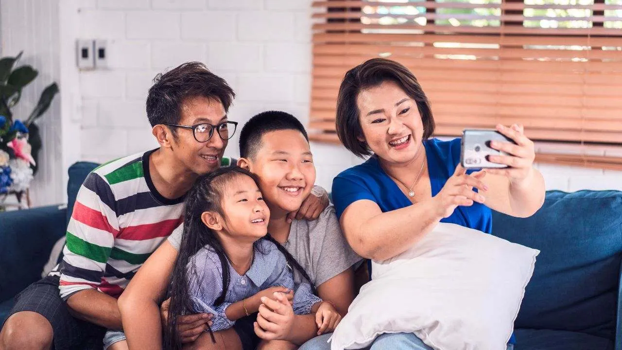 Une famille prend un selfie avec un smartphone dans son salon