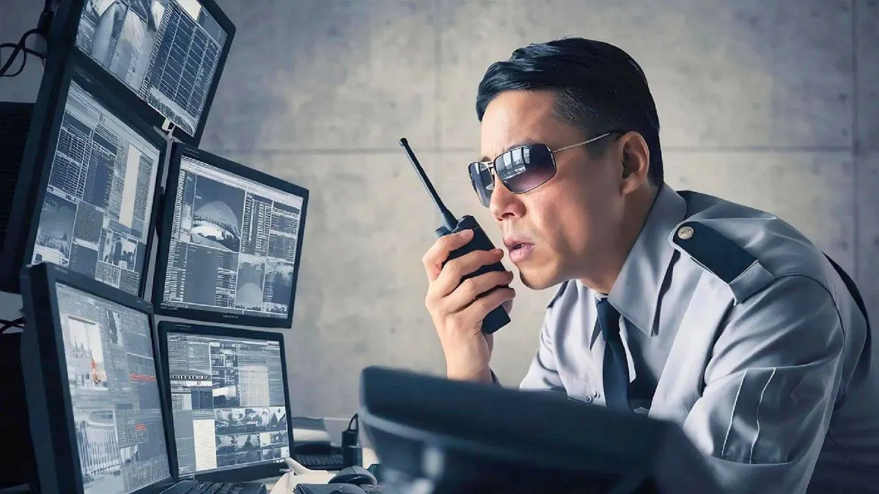 Agent de sécurité surveillant plusieurs écrans de contrôle dans un centre de vidéosurveillance en Thaïlande