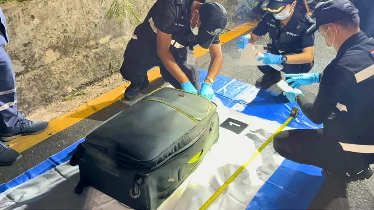 Des policiers scientifiques examinent la valise retrouvée près d'une voie ferrée à Pattaya, où le corps d'une adolescente de 17 ans a été découvert