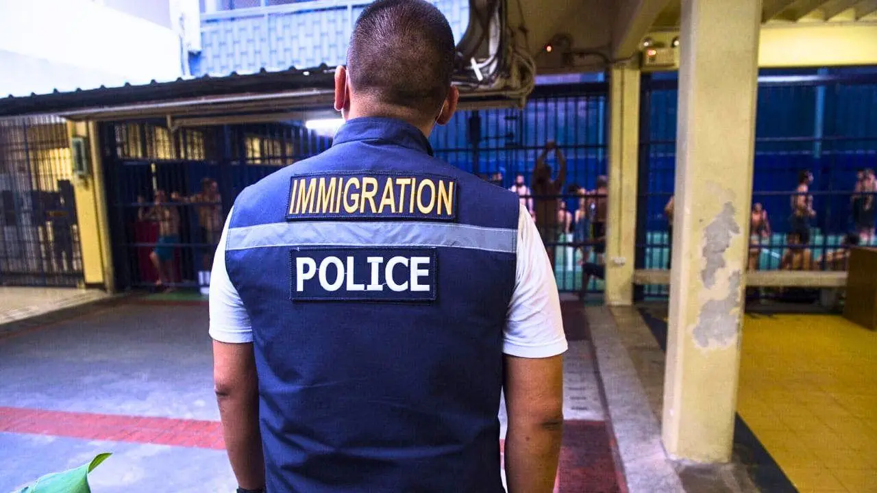 Agent de la police de l'immigration thaïlandaise devant des prisonniers