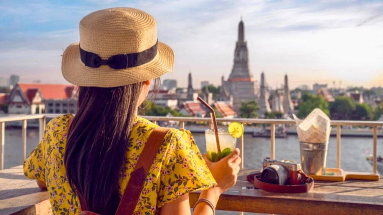 Une touriste boit un verre dans un bar en face du temple Wat Arun à Bangkok