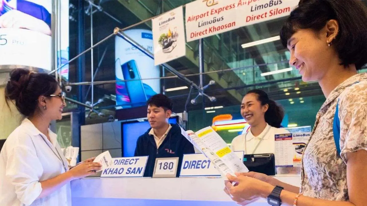 Des employés accueillent des voyageurs à un comptoir de transport touristique à Bangkok