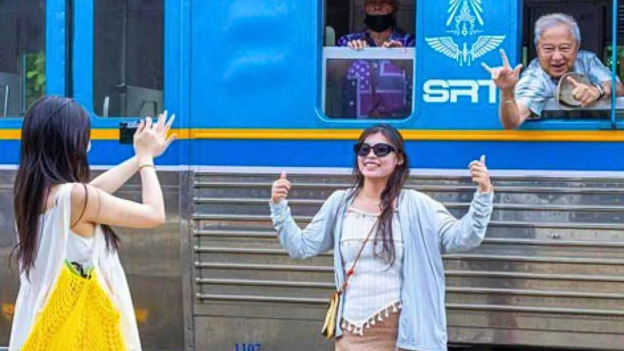 Touristes chinois prenant des photos devant un train de troisième classe à la gare de Chiang Mai en Thaïlande