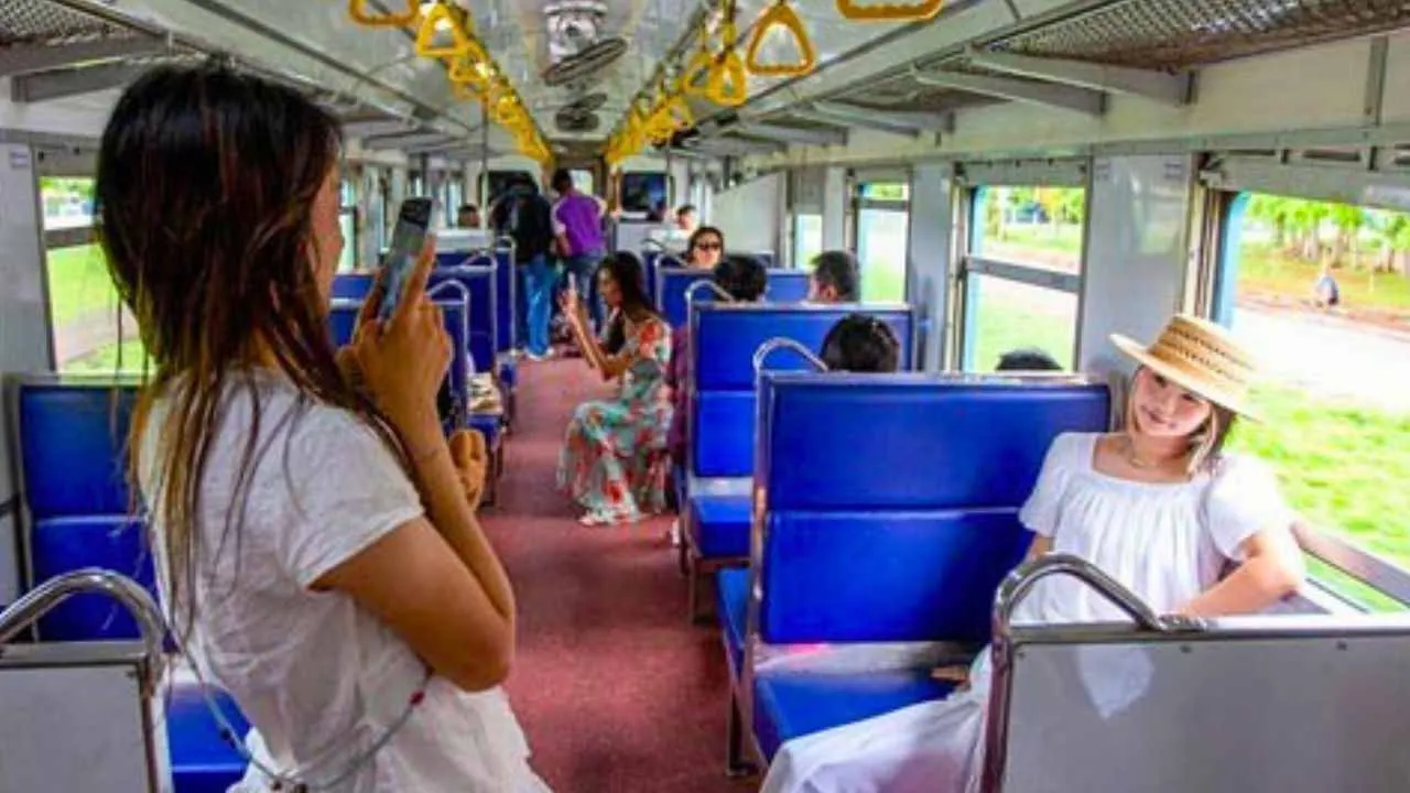 Des touristes prennent des photos à bord d'un train de troisième classe reliant Chiang Mai à Lamphun