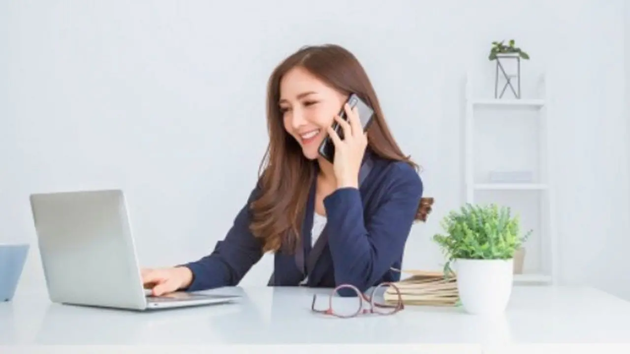 Employée travaillant sur un ordinateur portable tout en téléphonant