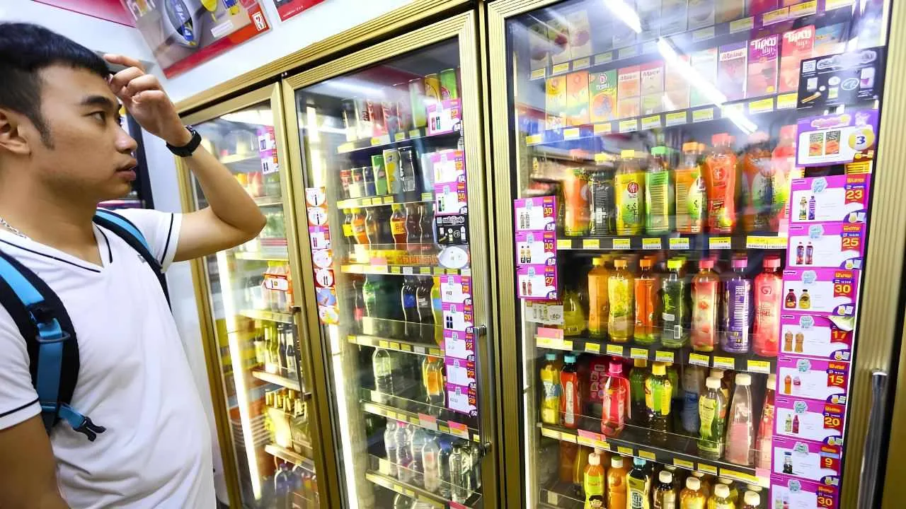 Un client évalue des boissons fraîches exposées dans une supérette de Bangkok