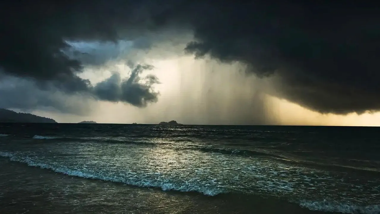 Rideau de fortes pluies au-dessus de la mer sous un ciel d'orage en Thaïlande