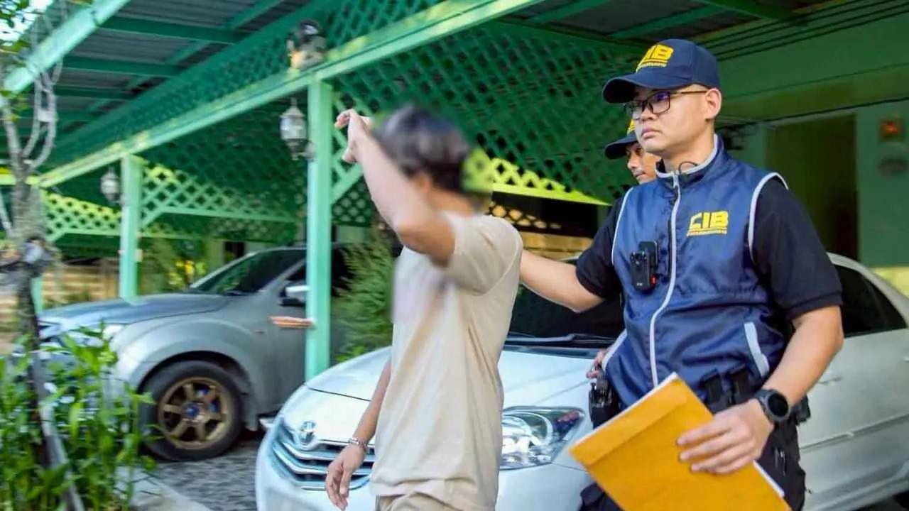 Un enquêteur du Bureau central des enquêtes (CIB) escorte le responsable d'un camp de muay thaï arrêté dans une affaire d'exploitation sexuelle de mineurs