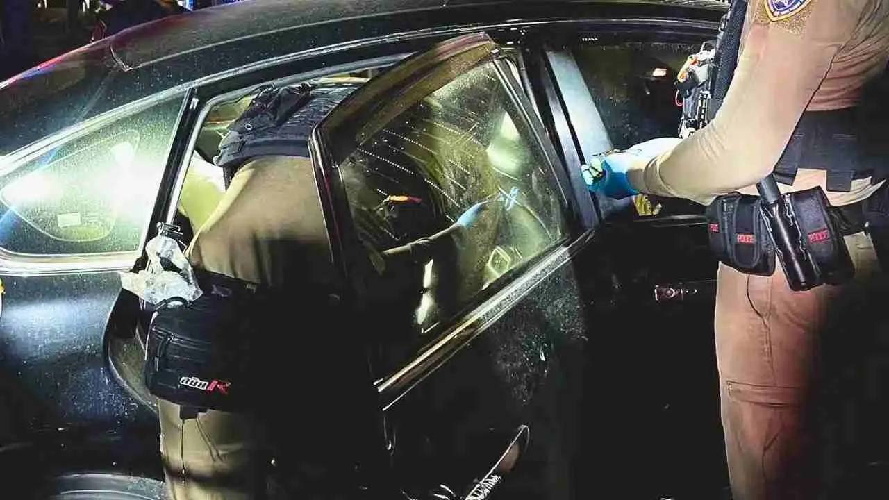 Policiers examinant l'intérieur d'une voiture après la découverte du corps d'une femme sur la banquette arrière à Samut Prakan