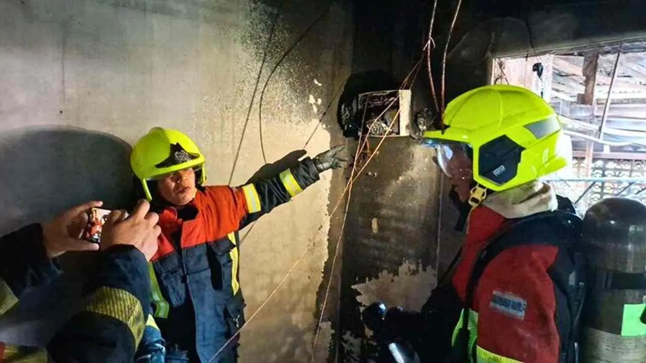 Pompiers inspectant un tableau électrique endommagé après l'incendie d'une maison à Bangkok