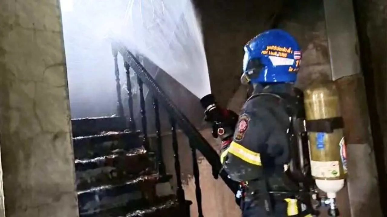 Pompier progressant dans un escalier enfumé lors de l'incendie d'une maison à Bangkok