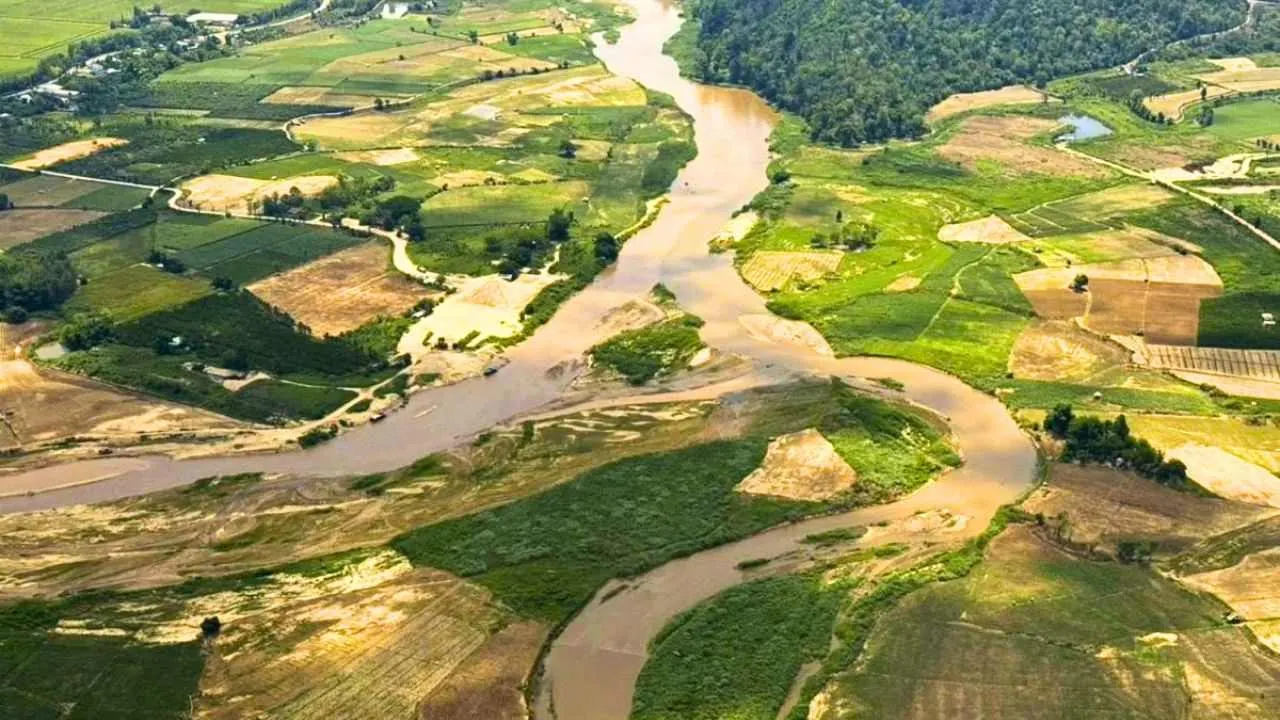 Vue aérienne de la rivière Kok, dont les eaux brun-rouge traversent des terres agricoles dans la province de Chiang Rai, après une pollution liée à des activités minières