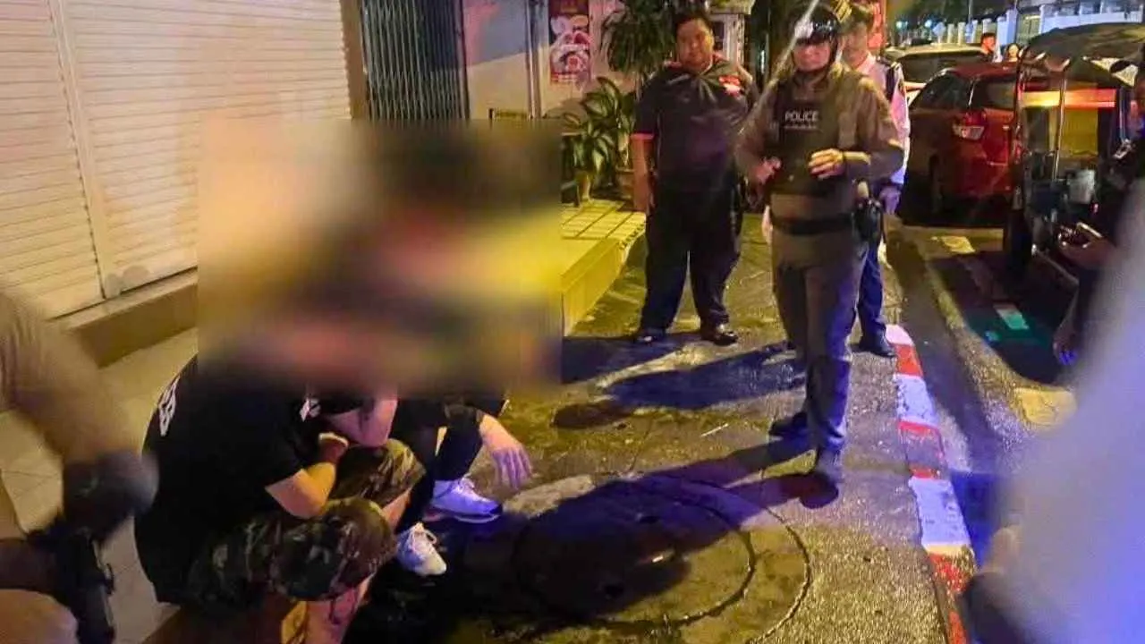 Deux touristes étrangers accroupis après leur interpellation par la police à Chiang Mai pour des graffitis