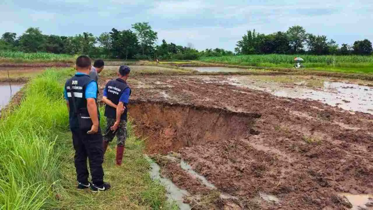 Des responsables inspectent l'un des gouffres géants apparus dans une rizière du district de Phu Pha Man, dans la province de Khon Kaen