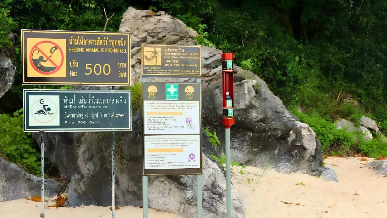 Panneaux d'information sur le risque de méduses-boîtes et borne de secours contenant du vinaigre sur une plage de Koh Samui, en Thaïlande