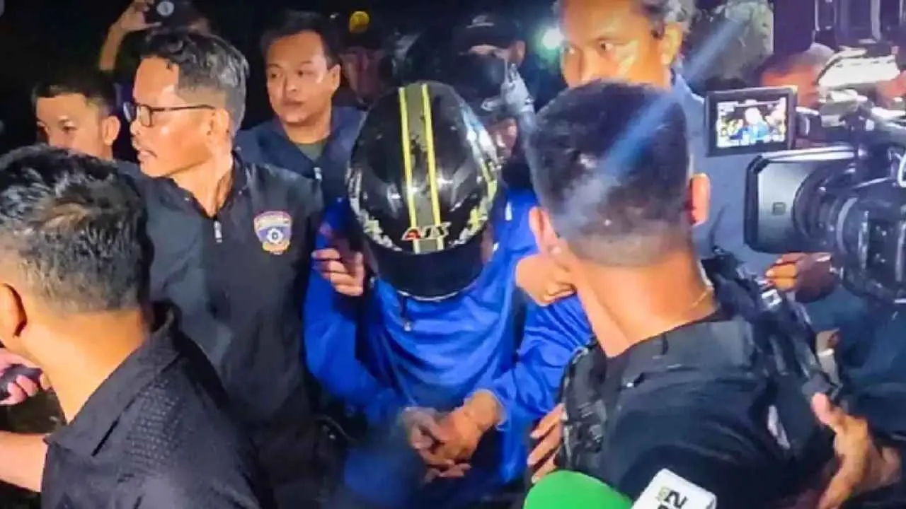 Un suspect portant un casque est escorté par la police thaïlandaise après son arrestation dans l'enquête sur les meurtres de Chonburi